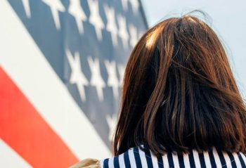 USA, back view of woman in front of Stars And Stripes